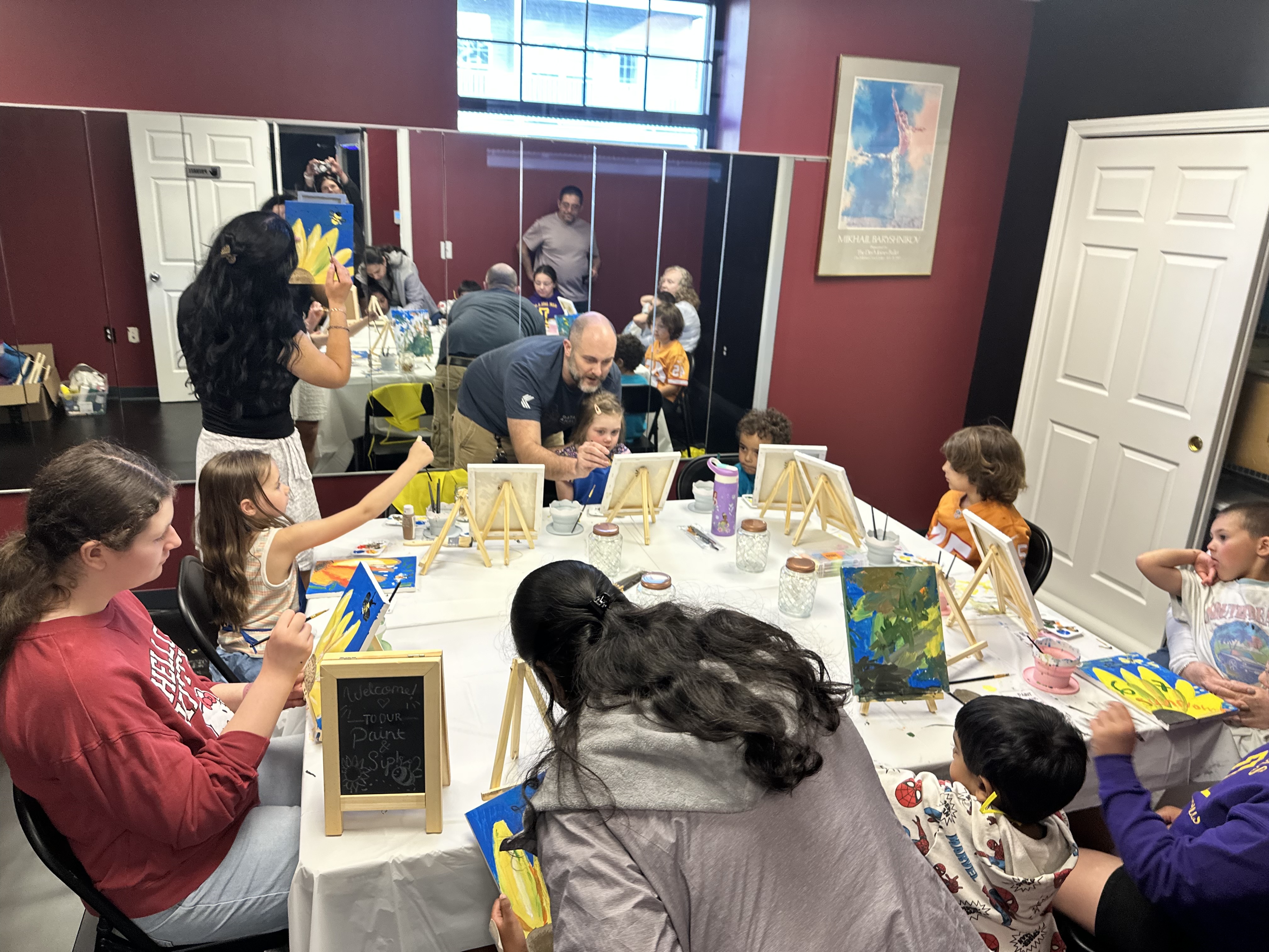 Teacher helping a child paint on an easel